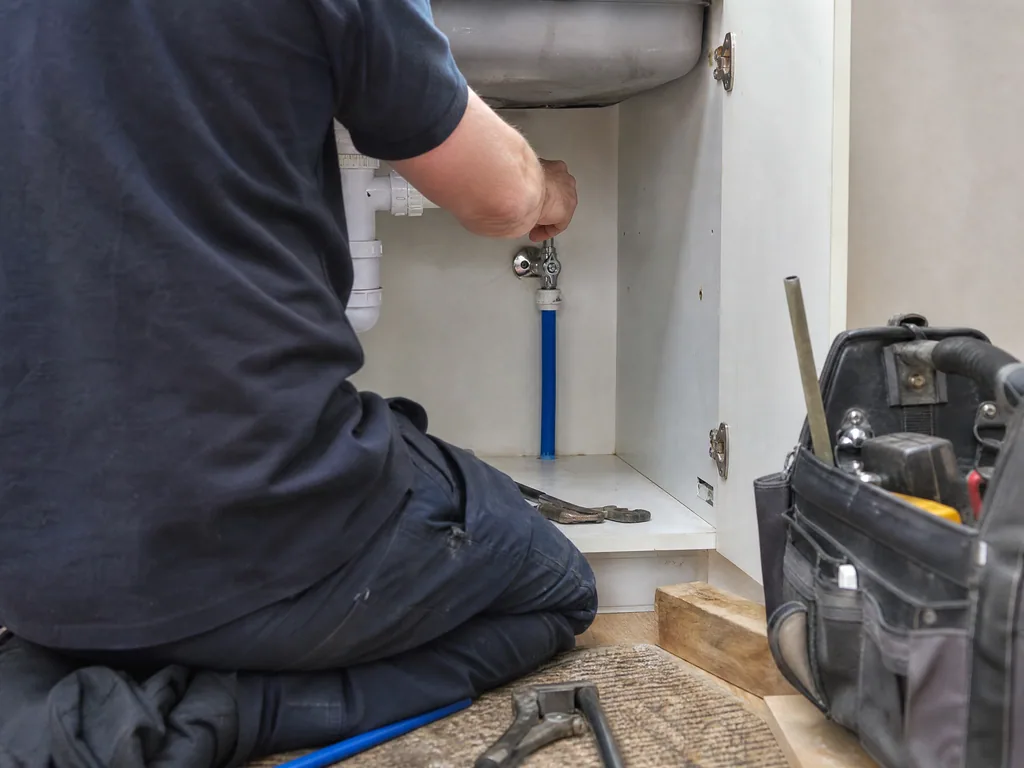 New blue supply pipe and stop tap fitted under a kitchen sink after lead pipe replacement, Nottingham