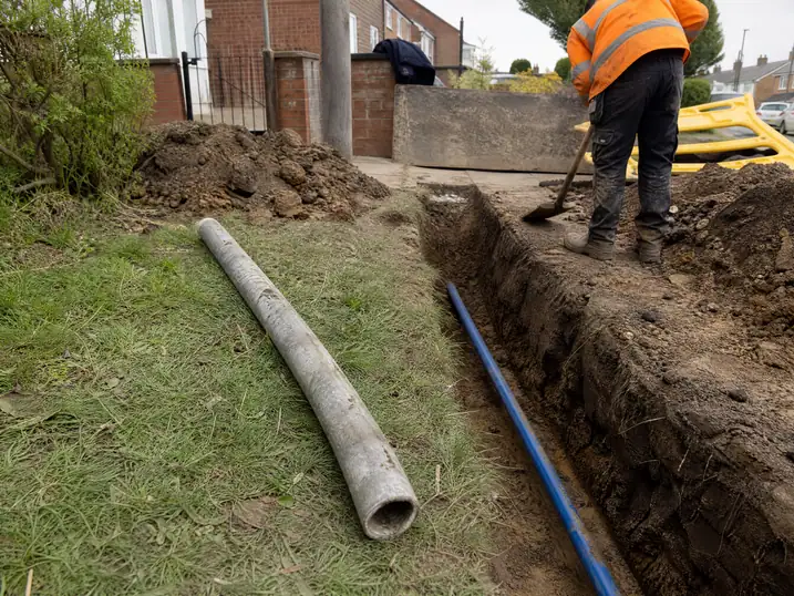 Old lead supply pipe lying beside the trench for its blue plastic replacement, Nottingham