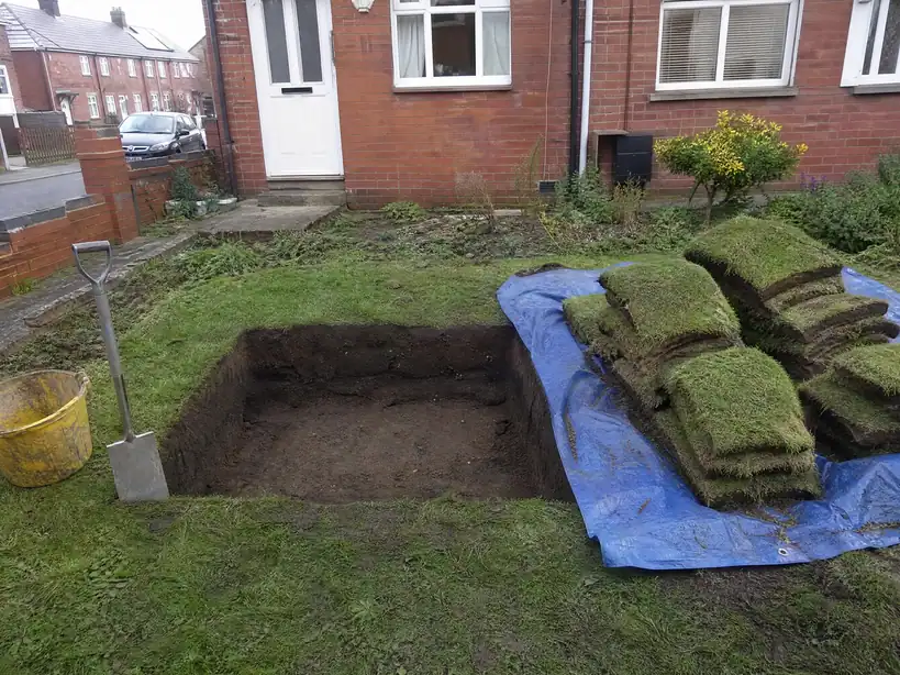 Repair hole dug in a front lawn with the turf stacked ready to relay, Nottingham